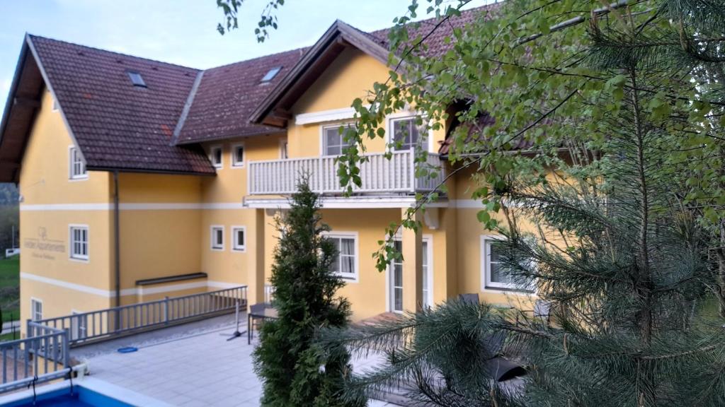 ein gelbes Haus mit einem Balkon und einem Pool in der Unterkunft Glanz und Gloria Velden! Wörthersee in 5 min zu Fuß erreichbar! in Velden am Wörthersee