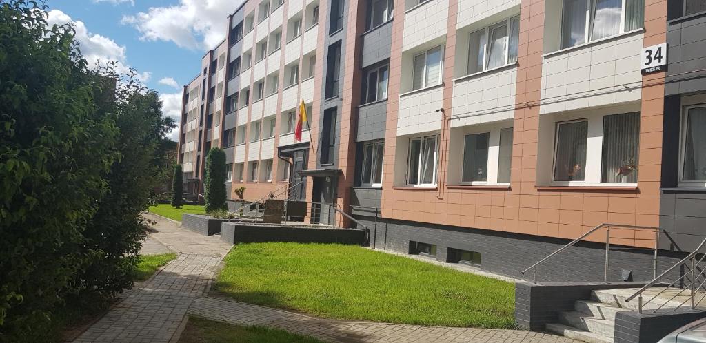 un bâtiment avec une cour herbeuse à côté d'un bâtiment dans l'établissement Apart Sauliaus, à Klaipėda