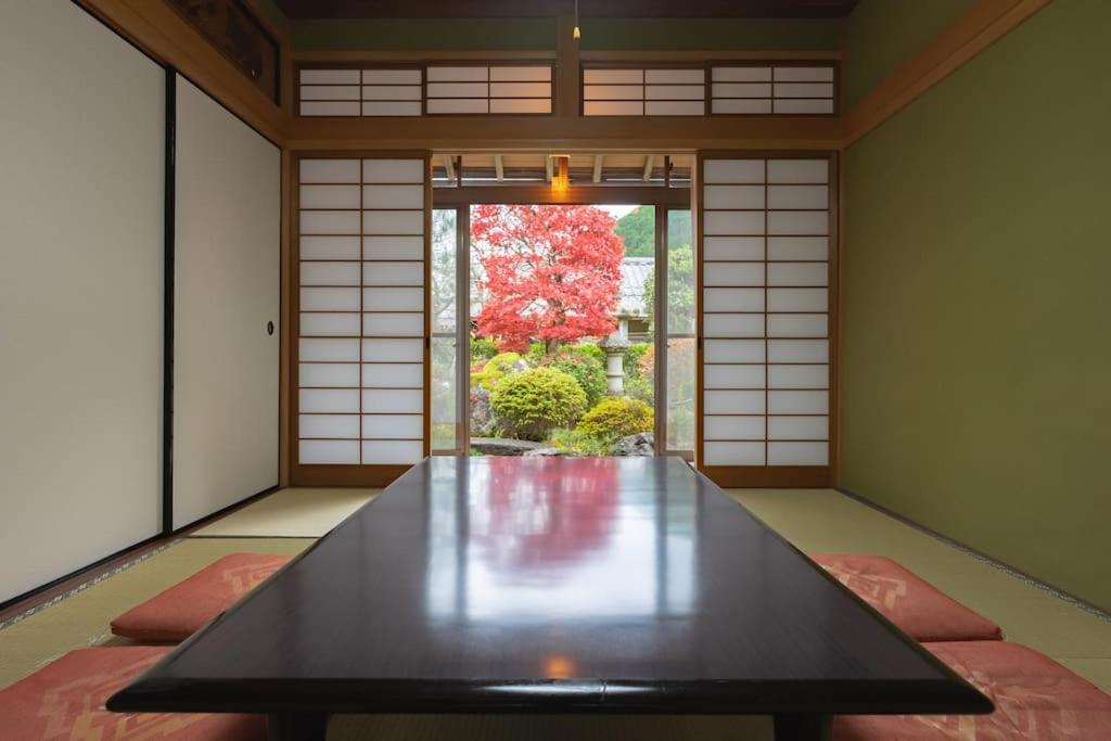 een eetkamer met een tafel en een deur naar een tuin bij 6 min walk from JR. Entire Traditional House w/ Zen Garden 