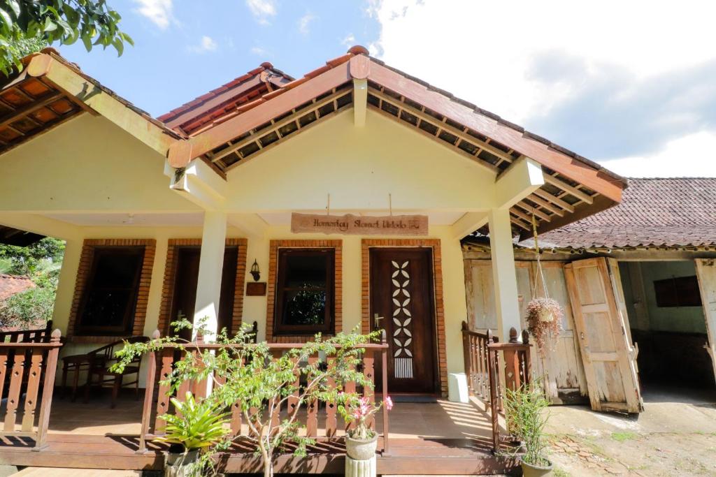 una pequeña casa amarilla con porche en Penginapan Widodo Syariah Borobudur, en Magelang