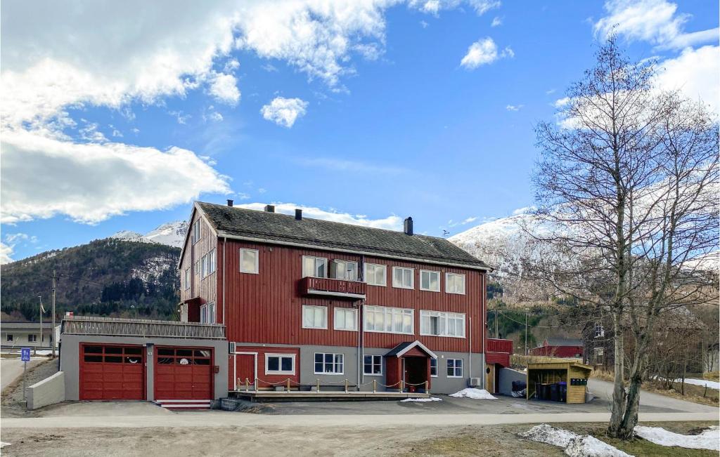 a large red building with mountains in the background at Pet Friendly Apartment In Tresfjord With Wifi in Tresfjord
