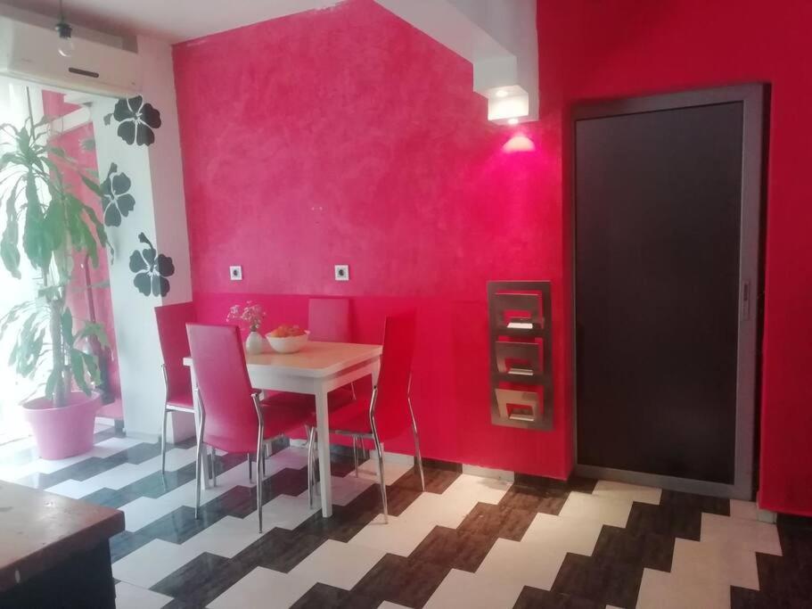 una sala da pranzo con tavolo e pareti rosa di Sofia Palms: Modern apartment with a large terrace a Sofia