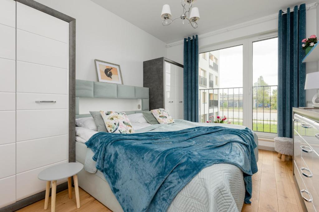 a bedroom with a bed with a blue blanket at Warsaw Kotsisa Apartments with Parking by Renters in Warsaw