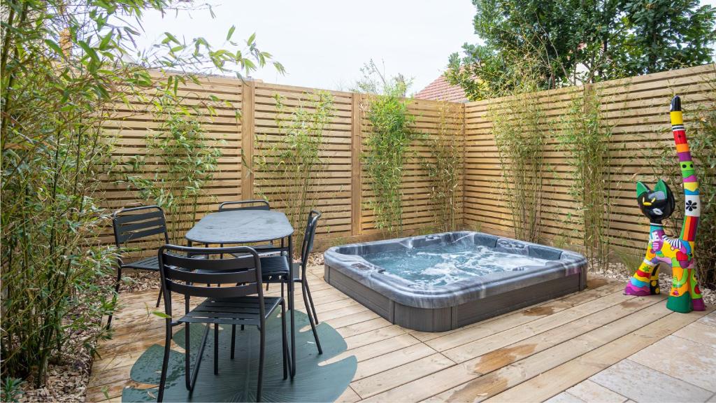 eine Terrasse mit einem Whirlpool, einem Tisch und Stühlen in der Unterkunft La villa MaRisKa et son SPA in Ouistreham