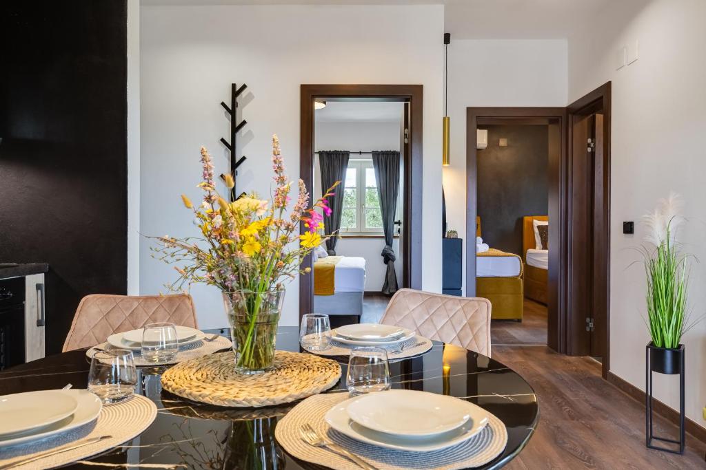 un comedor con una mesa con platos y flores. en TEONA Luxury Apartment with 2 rooms and terrace sea view, en Sali