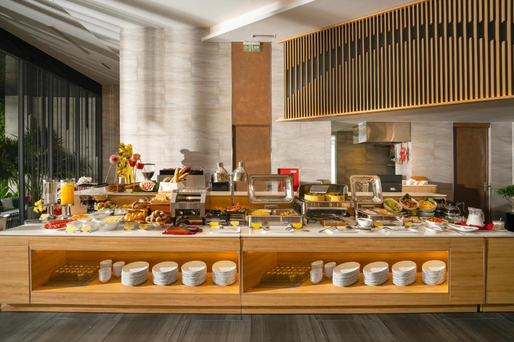 A large buffet counter displays hot dishes, pastries, fruit, drinks and tableware.