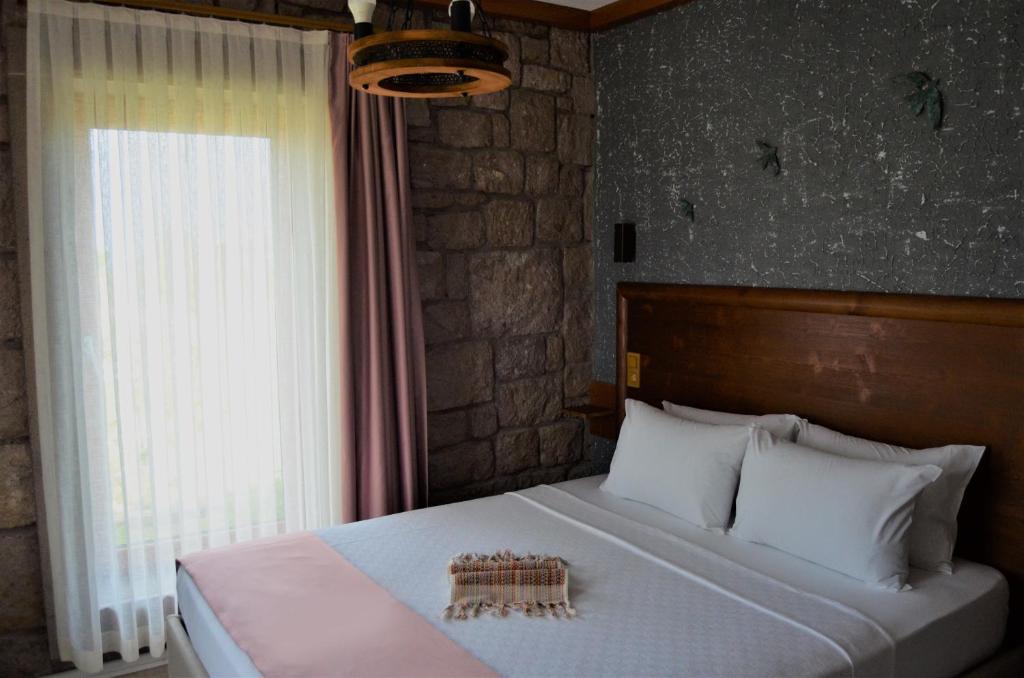 Le Petit Hotel ve Bağ Evi في بوزجادا: غرفة نوم بسرير كبير مع نافذة