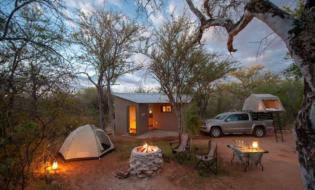 a campsite with a tent and a car and a table with a fire at Onguma Tamboti Campsite in Namutoni