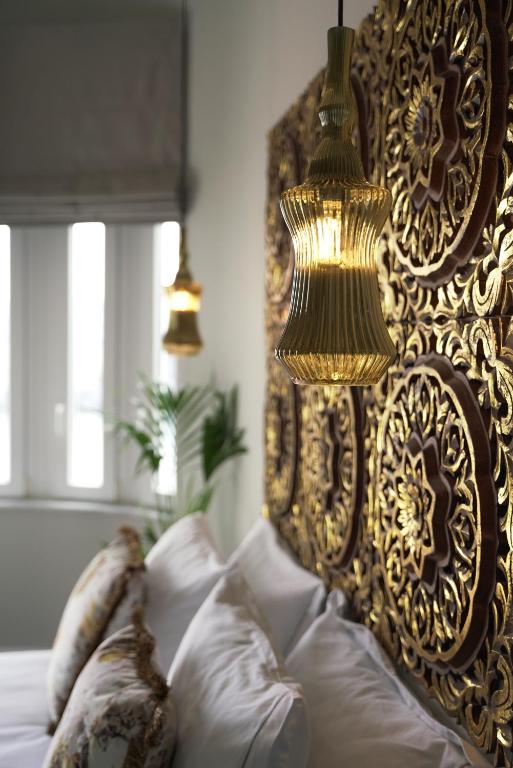 a bed with a gold head board with pillows at Pafsilipon Suites in Ermoupoli
