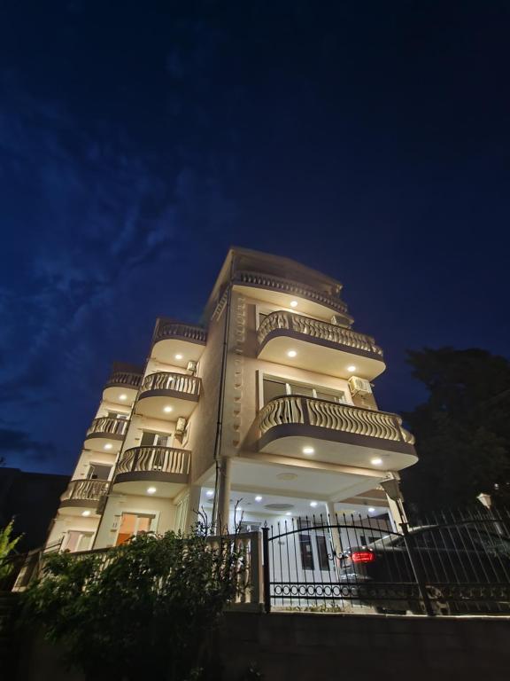 un edificio alto de color blanco con balcones por la noche en Apartments Adriatik, en Ulcinj