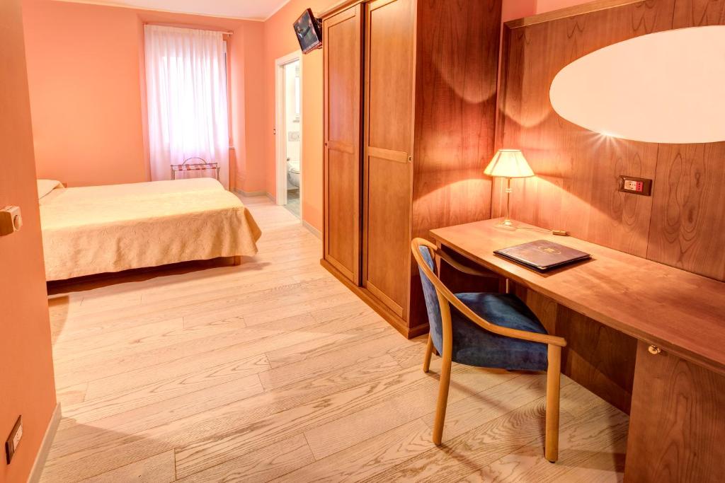 Camera d'albergo con scrivania, letto e sidx sidx sidx. di Hotel Italia a Trieste