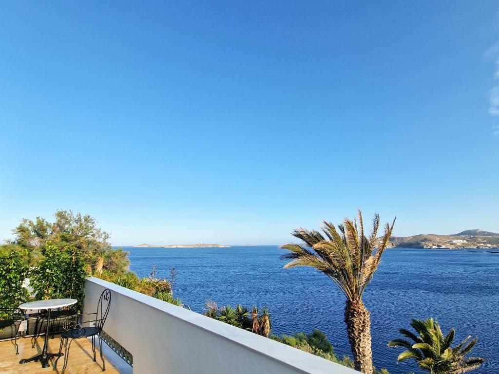 a view of the ocean from a balcony with a palm tree at Pafsilipon Suites in Ermoupoli