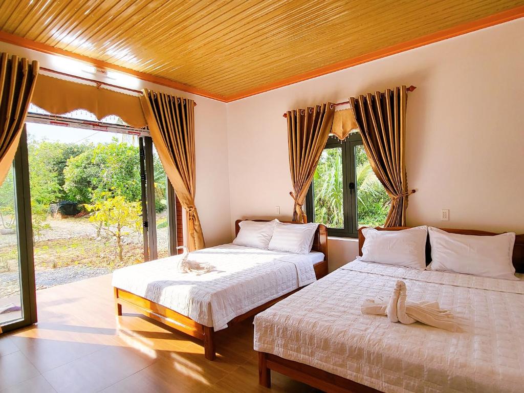 a bedroom with two beds and a large window at Thuy Tien Ecolodge in Cat Tien