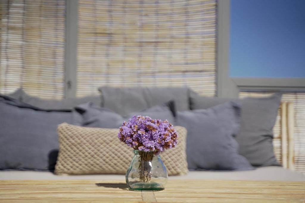 a glass vase with purple flowers sitting on a table at Pafsilipon Suites in Ermoupoli