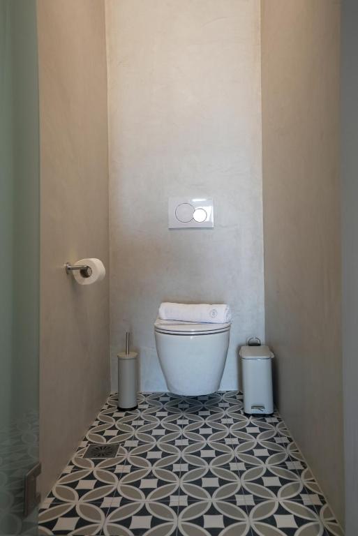 a bathroom with a toilet and a black and white tile floor at Pafsilipon Suites in Ermoupoli