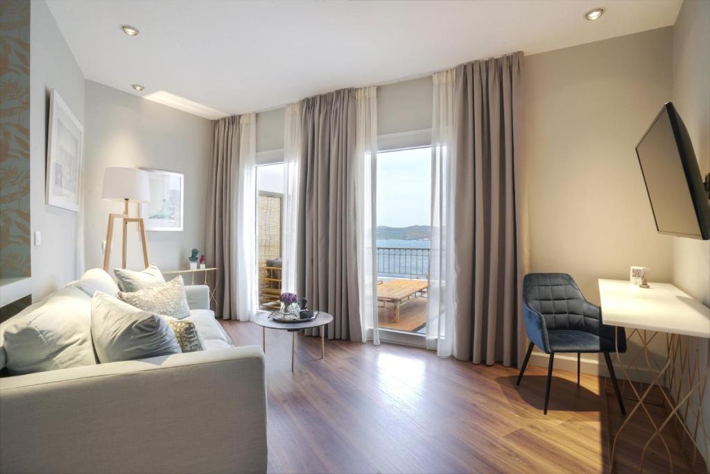a living room with a white couch and a large window at Pafsilipon Suites in Ermoupoli