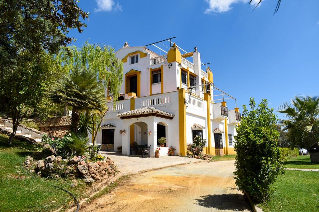 Finca La Lola - Large House with private pool في أرشذونة: بيت كبير اصفر وبيضاء بالاشجار والعشب