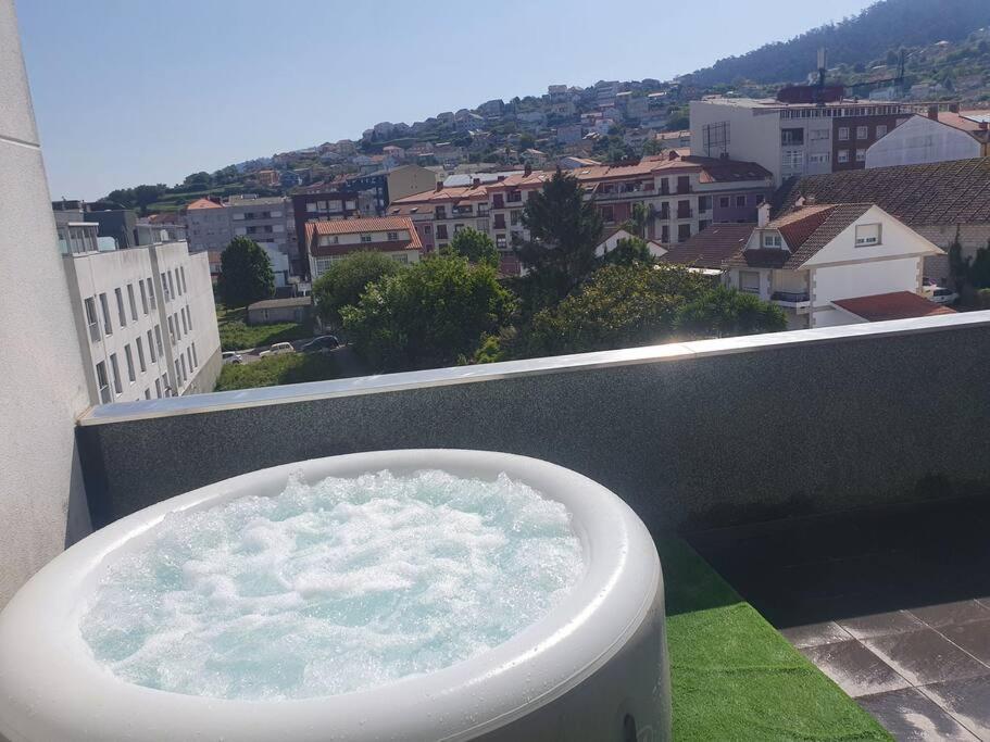a bath tub on a balcony with a view of a city at Alojamiento de relax y romanticismo ! in Bueu