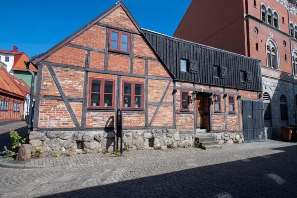 Um velho edifício de tijolos com um homem à frente dele. em Entire house in the center em Ystad