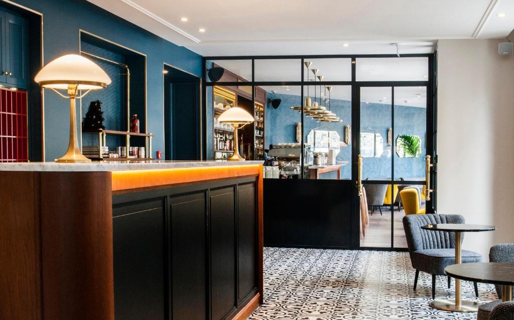 a bar in a restaurant with blue walls and tables at Hotel André Latin in Paris