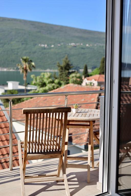 a wooden bench sitting on a balcony with a table at Little Sunshine in Herceg-Novi
