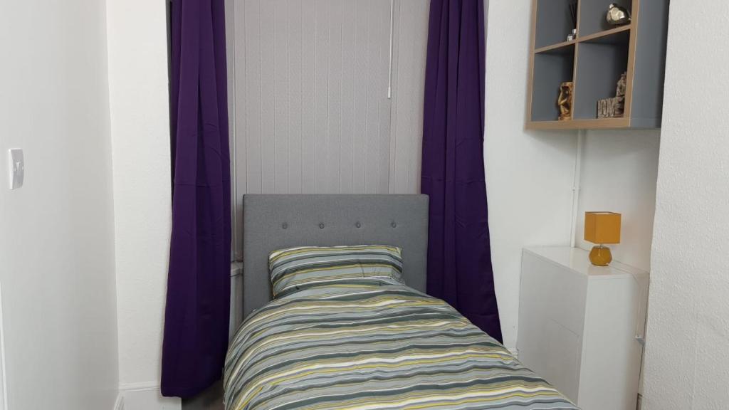 a bed in a room with purple curtains at Kunda House Parkhill in Birmingham