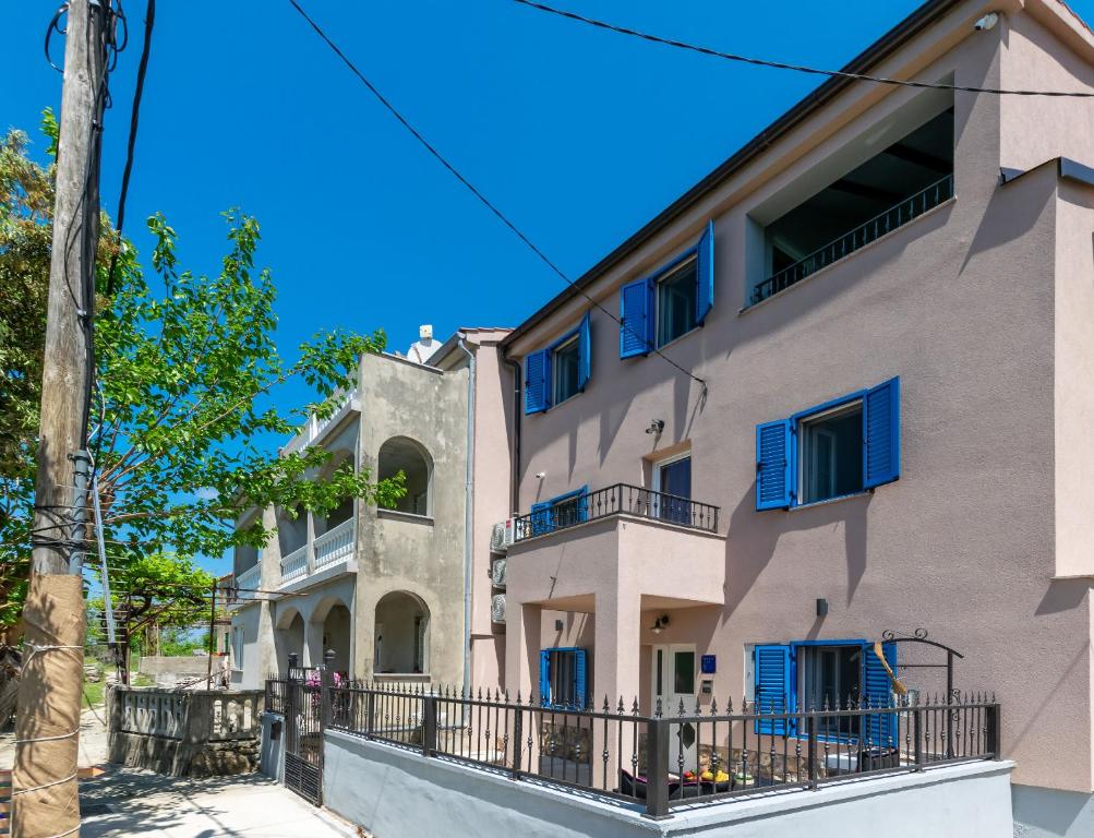 an apartment building with blue windows and a balcony at House Villa Vito in Lopar