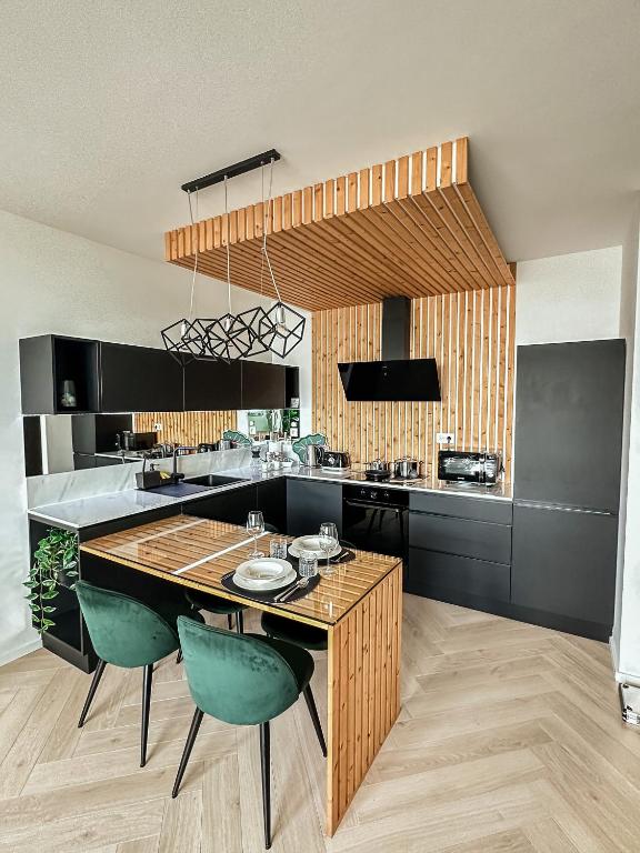 a kitchen with a wooden table and green chairs at Luxusný apartmán na 21 poschodí s parkovaním zadarmo BA in Bratislava