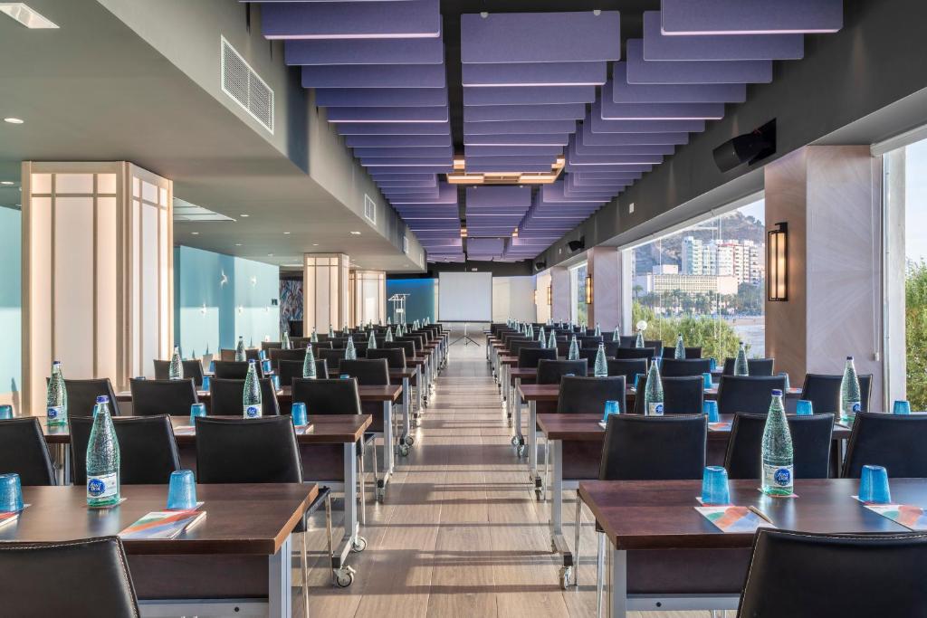 a row of tables and chairs in a room with windows at Melia Alicante in Alicante