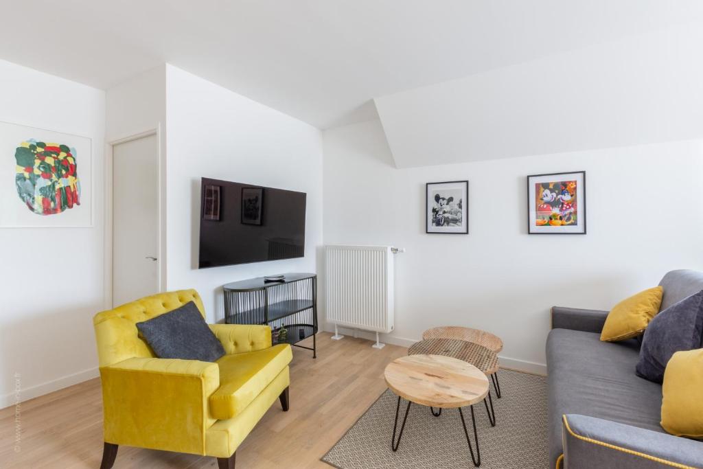 a living room with a couch and a chair and a tv at Sur un Nuage by Plaza in Serris