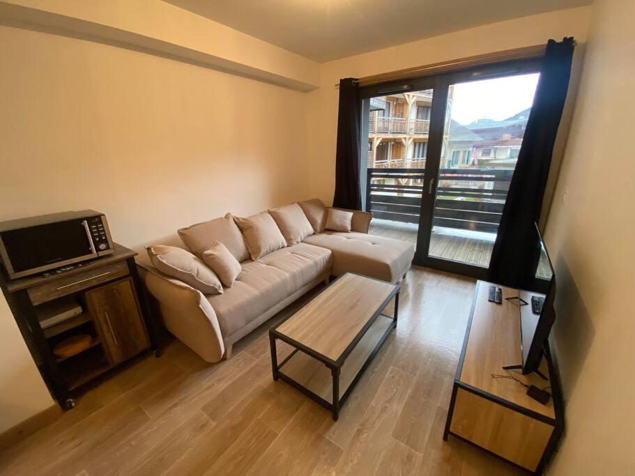 a living room with a couch and a table and a window at Appartement très cosy en plein centre in Les Gets