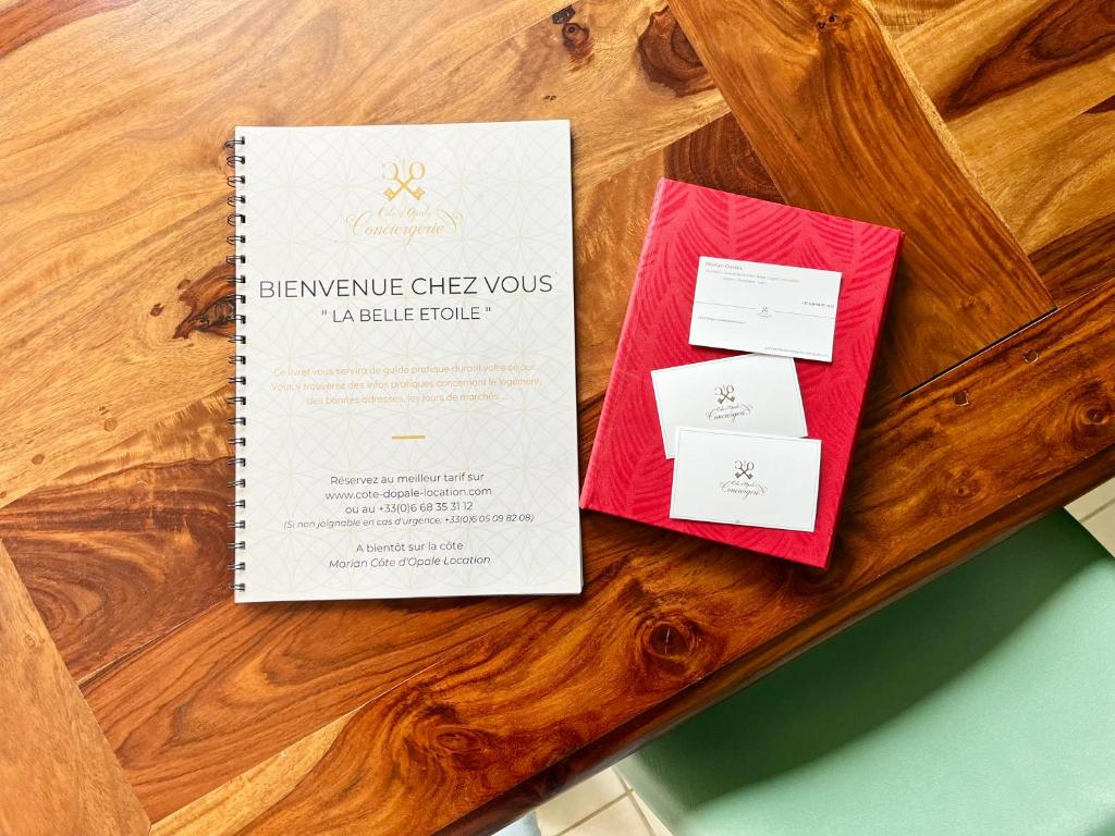 a spiral notebook on a wooden table with certificates and envelopes at COC - La Belle Etoile in Wissant
