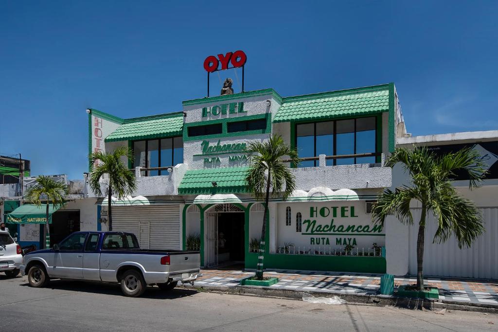 a truck parked in front of a hotel with palm trees at OYO Hotel Nachancan in Chetumal