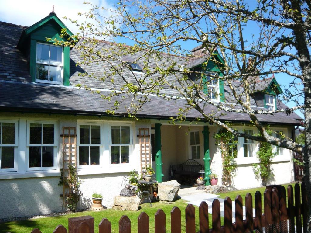 ein weißes Haus mit einem Zaun davor in der Unterkunft Ivy Cottage Bed and Breakfast in Braemar