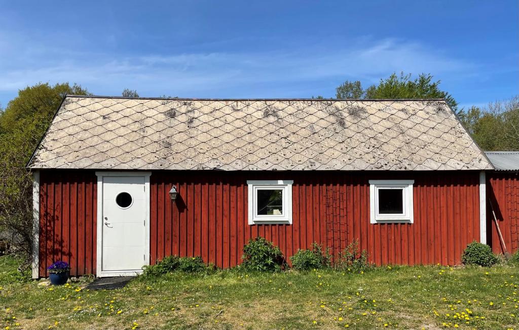 eine rote Scheune mit einer weißen Tür und Fenstern in der Unterkunft Lugnet in Hörby