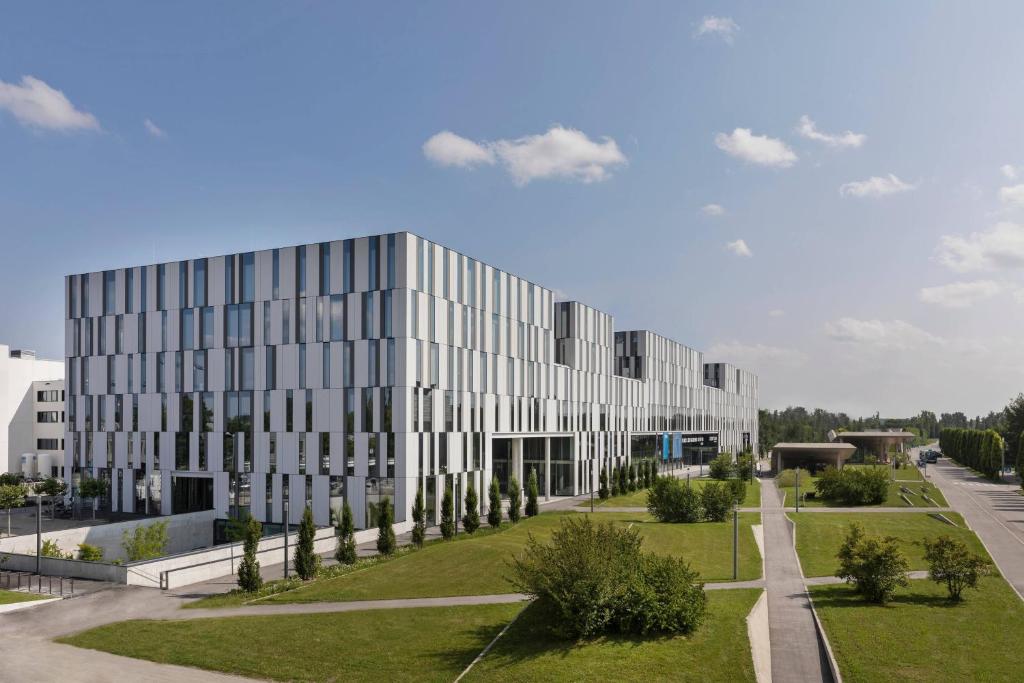 un gran edificio blanco con árboles delante de él en Courtyard by Marriott Munich Garching, en Garching bei München