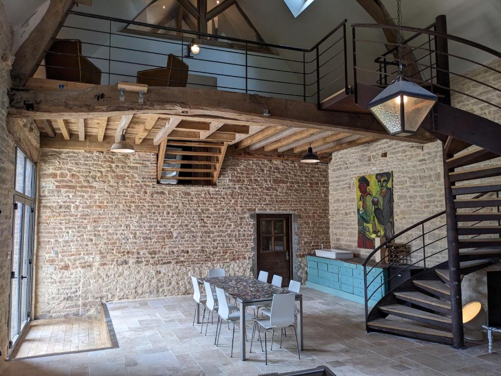 Habitación con mesa, sillas y pared de ladrillo. en La Grange de la Porterie - Magnificent House and Barn Conversion in Historic village, en Chapaize