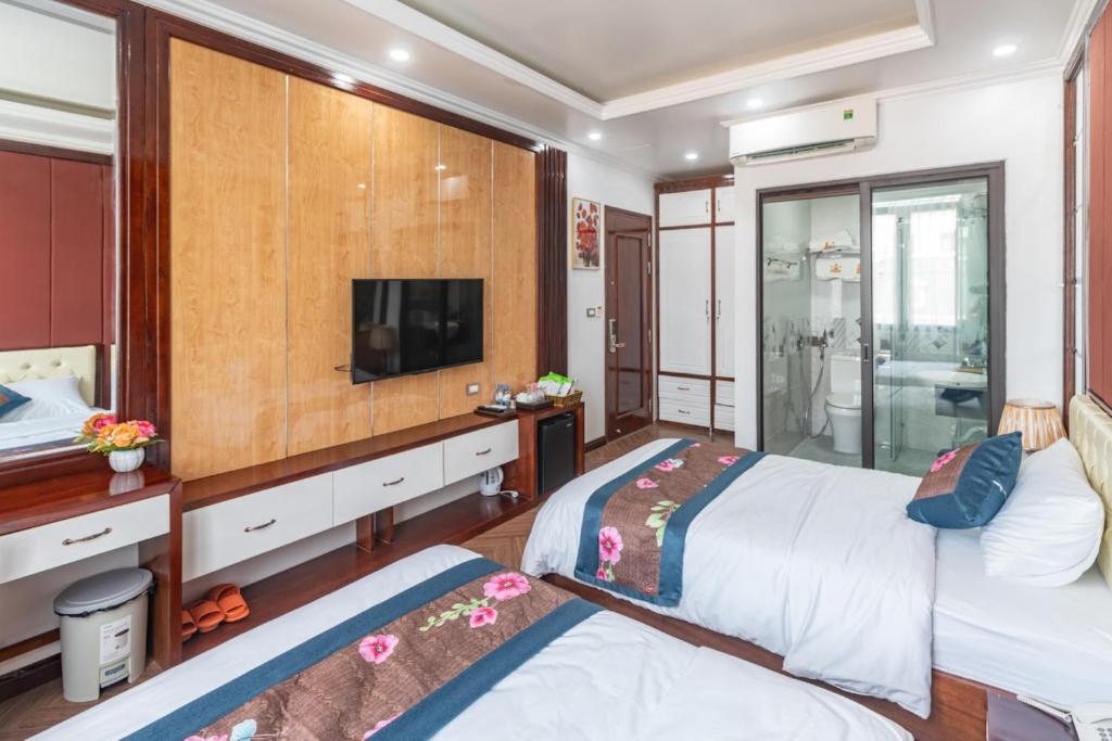 a bedroom with two beds and a flat screen tv at Hương Nam Hotel in Ha Long