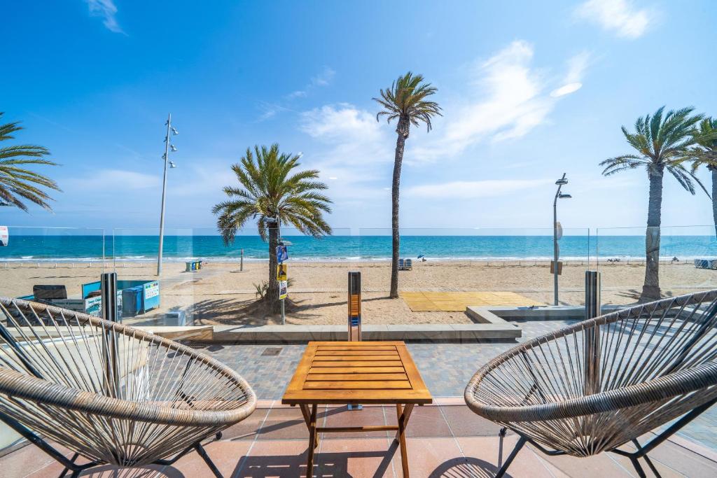 a table and two chairs in front of a beach at La Casa del Pescador Calafellmar in Calafell