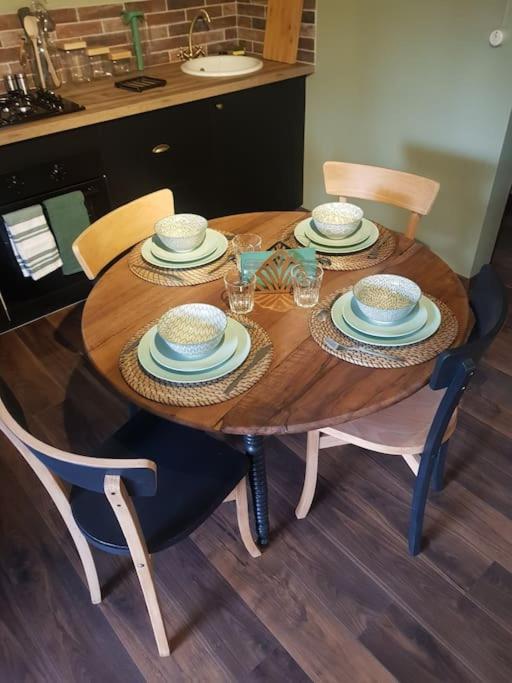 - une table en bois avec des chaises, des assiettes et des verres dans l'établissement L’expérience BrocAndBric, à Amboise