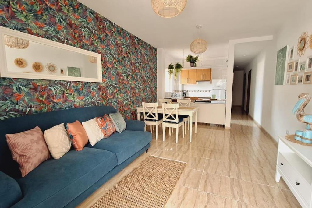 sala de estar con sofá azul y cocina en Tropical Apartment - Heated Pool en El Palmar