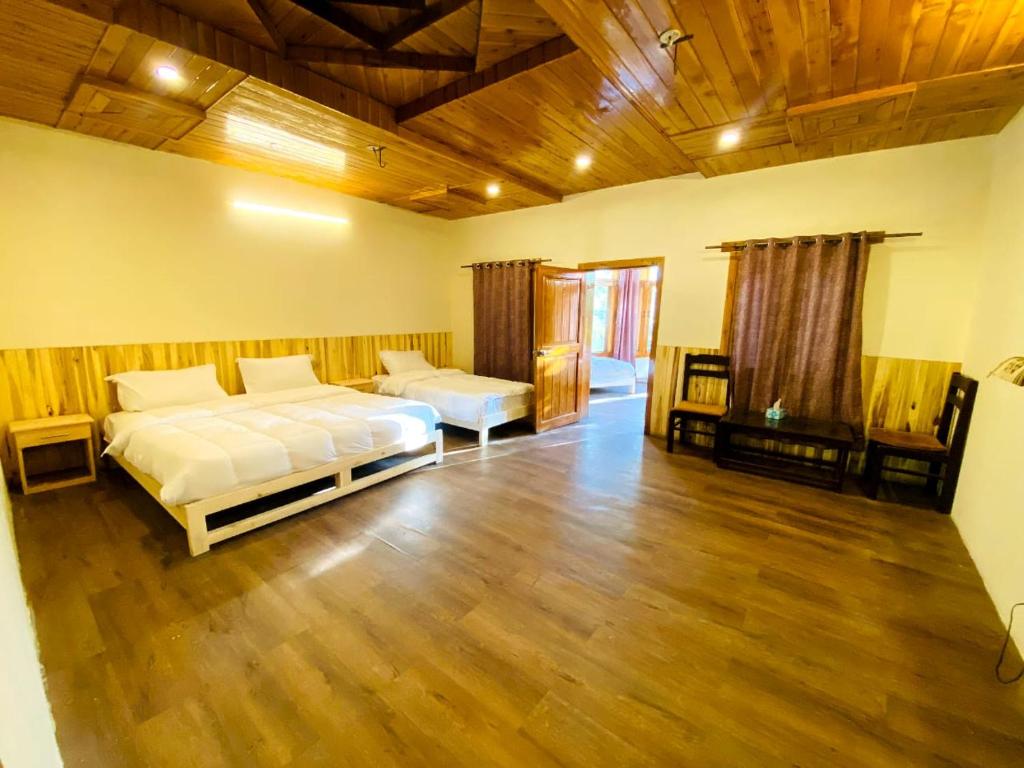 1 dormitorio con 2 camas y suelo de madera en Manasau Resort, en Hunza