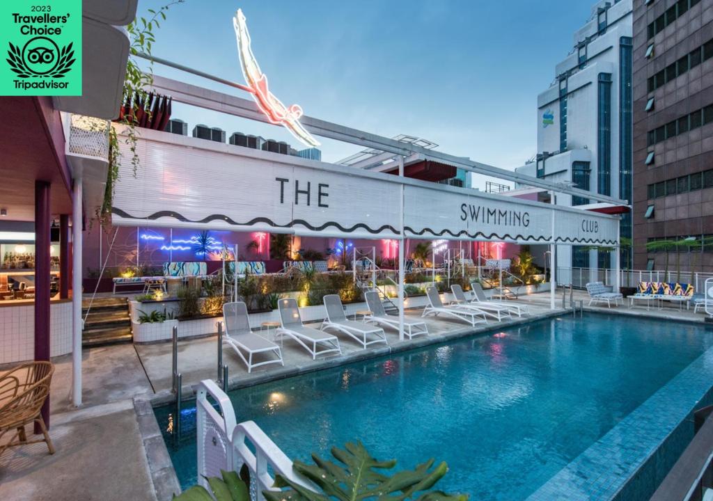 a swimming pool with white chairs next to a building at The Kuala Lumpur Journal Hotel in Kuala Lumpur