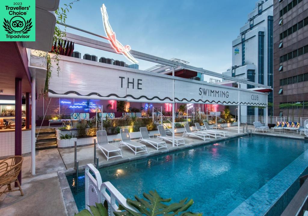 una piscina con sillas blancas junto a un edificio en The Kuala Lumpur Journal Hotel, en Kuala Lumpur