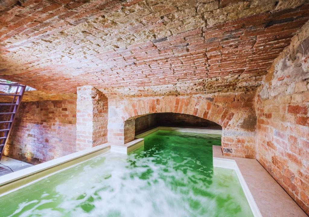 uma piscina de água verde numa parede de tijolos em CountryHouse con Piscina Privata Vicina al Centro em Florença