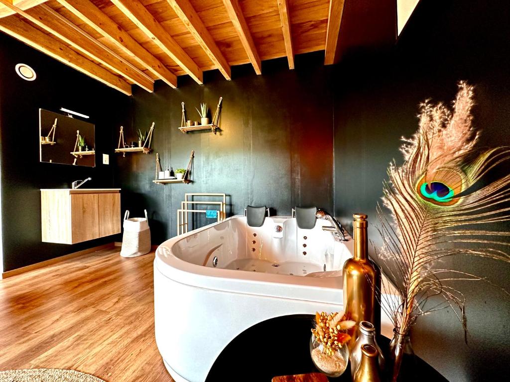uma banheira branca num quarto com tecto em madeira em Hour House - Esc'Appart em Houyet