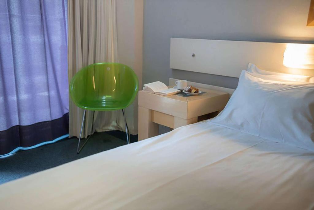 1 dormitorio con cama, escritorio y silla verde en Dorian Inn - Sure Hotel Collection by Best Western, en Atenas