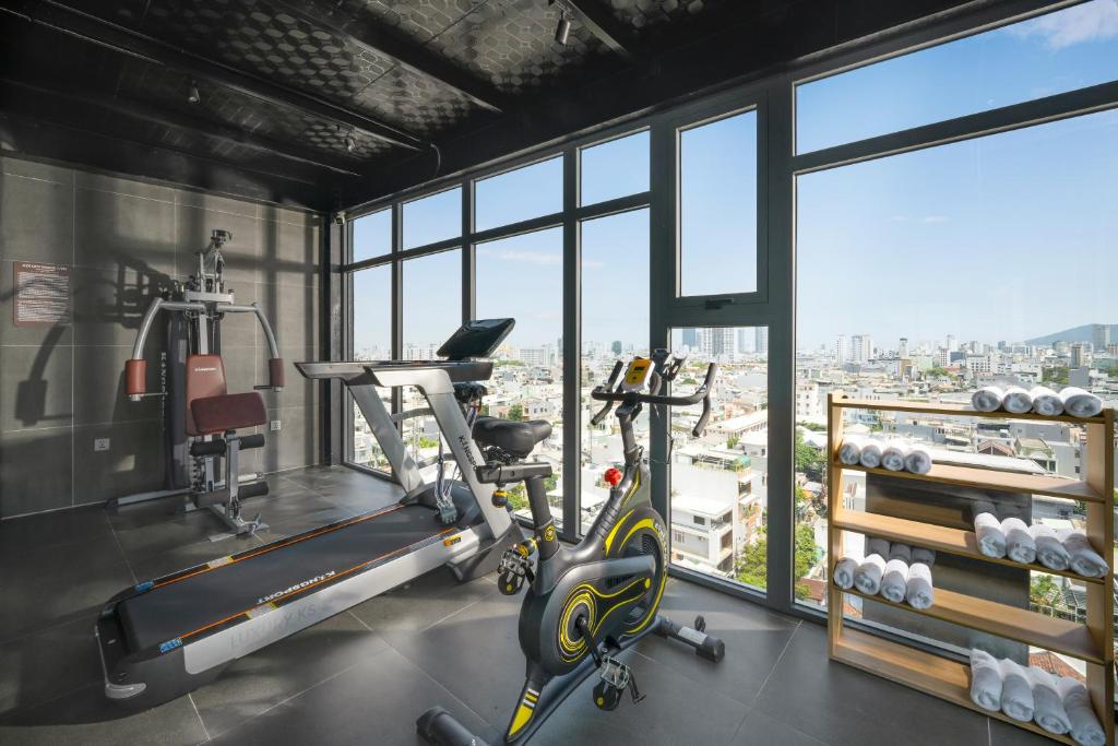 A bright gym with cardio machines, a weight station and city views.