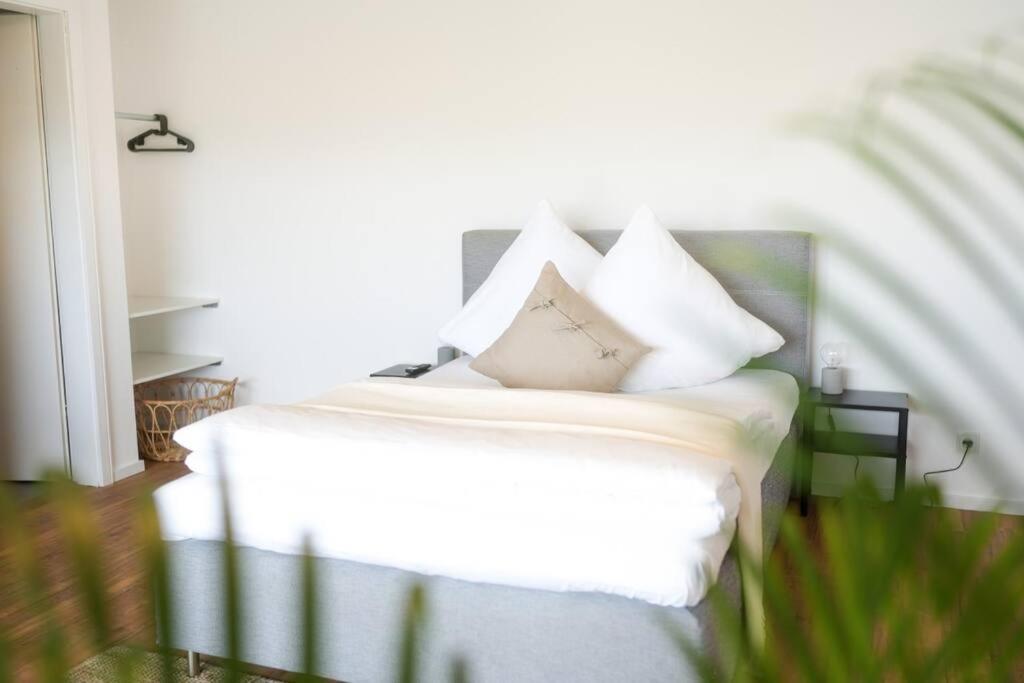 ein Bett mit weißer Bettwäsche und Kissen darauf in der Unterkunft Luxuriöse Wohnung mit Flussblick nahe Stadtzentrum in Koblenz
