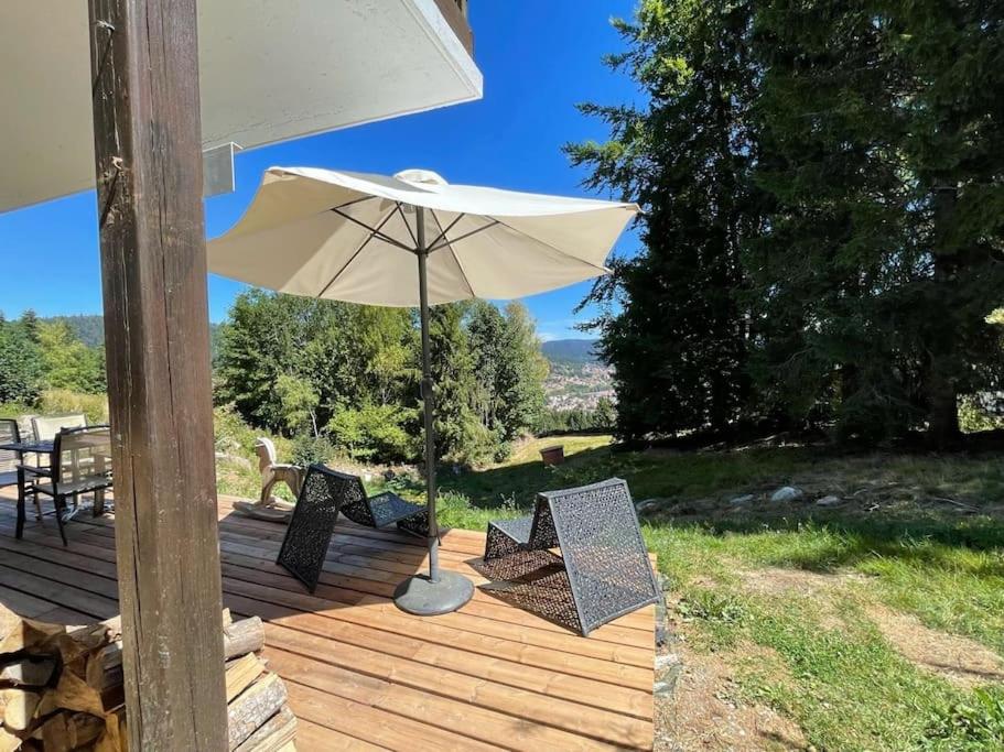 an umbrella and chairs on a wooden deck at La Gallerie du Domaine des lupins in Xonrupt-Longemer